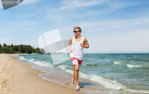 Image of happy man running along summer beach