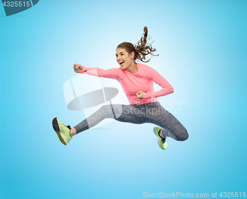 Image of happy sporty young woman jumping in fighting pose