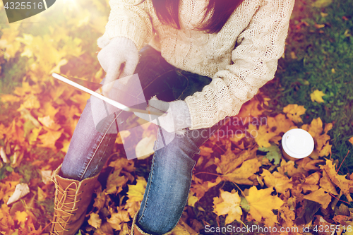 Image of woman with tablet pc and coffee in autumn park