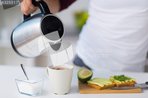 Image of man with kettle making tea for breakfast at home