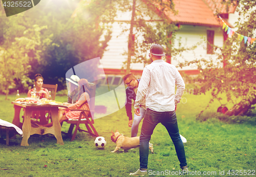 Image of friends playing football with dog at summer garden