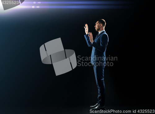 Image of businessman in suit touching something invisible