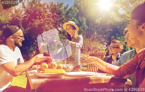 Image of happy friends having dinner at summer garden party