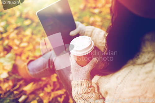 Image of woman with tablet pc and coffee in autumn park