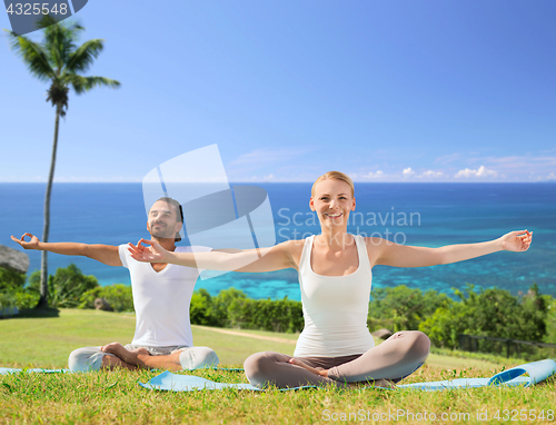 Image of couple doing yoga in lotus pose outdoors