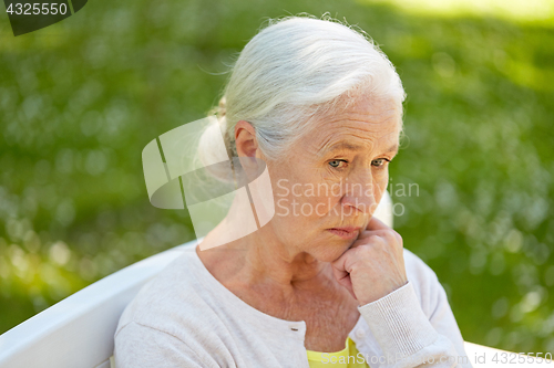 Image of sad senior woman sitting on bench at summer park