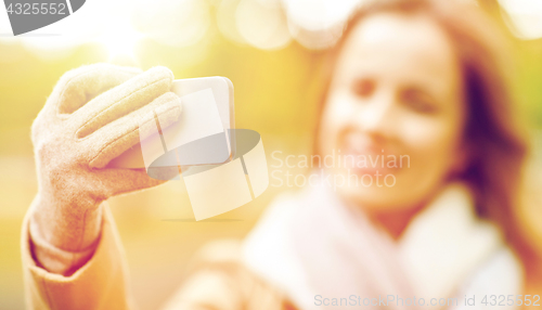 Image of woman taking selfie by smartphone in autumn park