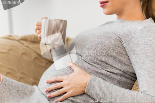 Image of happy pregnant woman with cup drinking tea at home