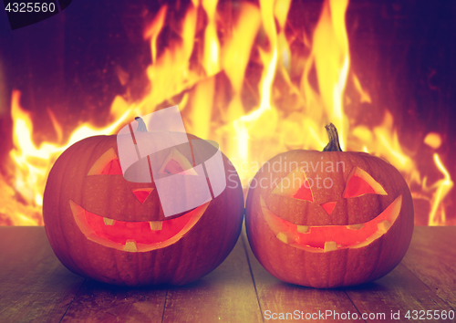 Image of carved halloween pumpkins on table over fire