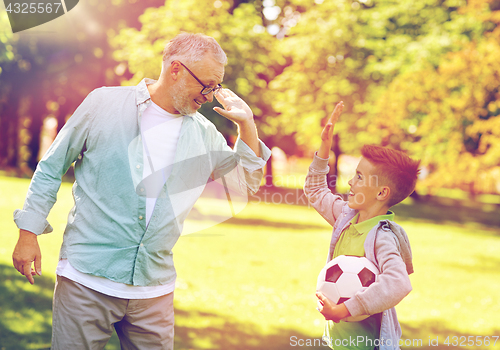 Image of old man and boy with soccer ball making high five
