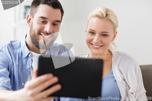 Image of smiling happy couple with tablet pc at home