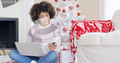 Image of Young woman purchasing Christmas gifts online