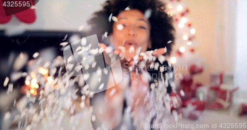 Image of Young woman blowing confetti off her hands
