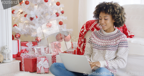 Image of Young woman typing on a laptop at Christmas