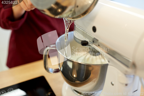 Image of chef pouring ingredient from pot into mixer bowl