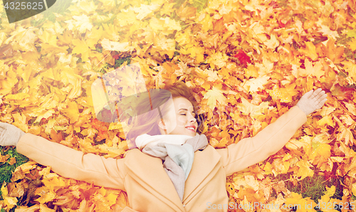 Image of beautiful happy woman lying on autumn leaves