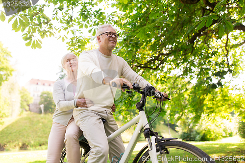 Image of happy senior couple riding on bicycle at park