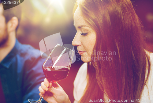 Image of smiling woman drinking red wine at restaurant