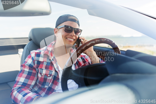 Image of happy man calling on smartphone in convertible car