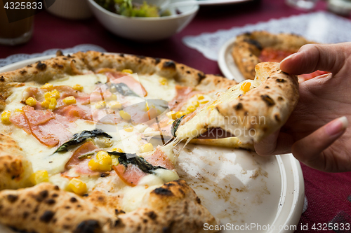 Image of Hand taking out sliced of pizza