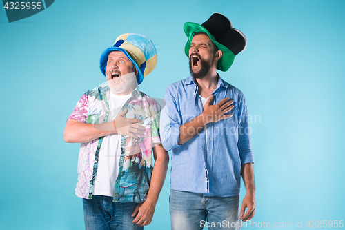 Image of The two football fans singing the national anthem over blue