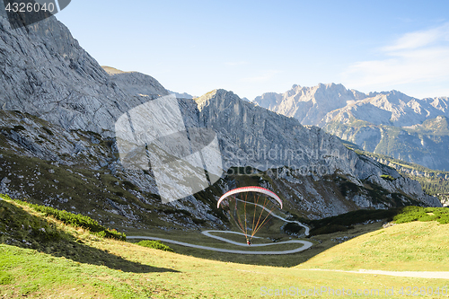 Image of Alpine landscape with hovering paraglider