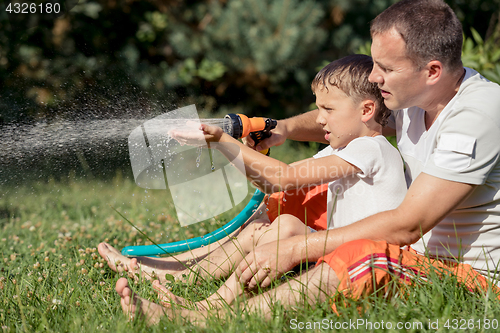 Image of Happy father and son playing in the garden at the day time. 