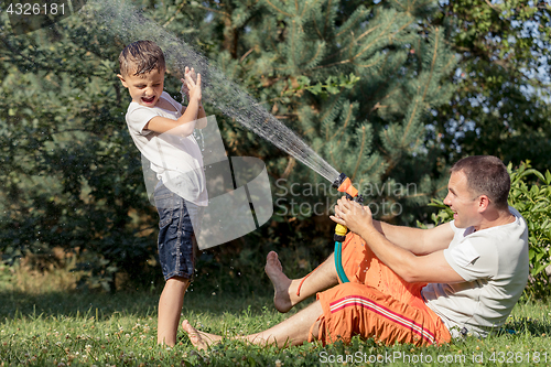 Image of Happy father and son playing in the garden at the day time.