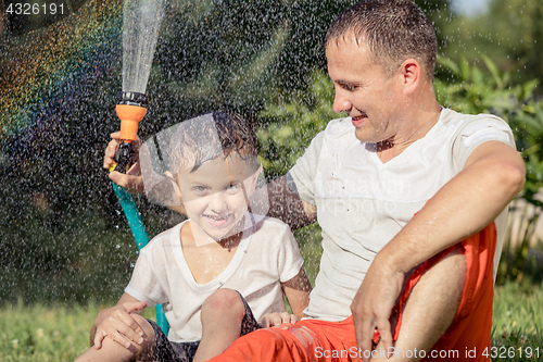 Image of Happy father and son playing in the garden at the day time.