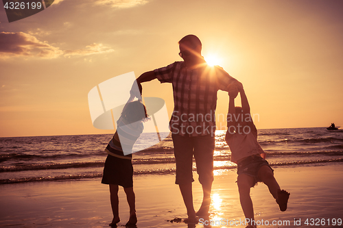 Image of Father and children playing on the beach at the sunset time. 