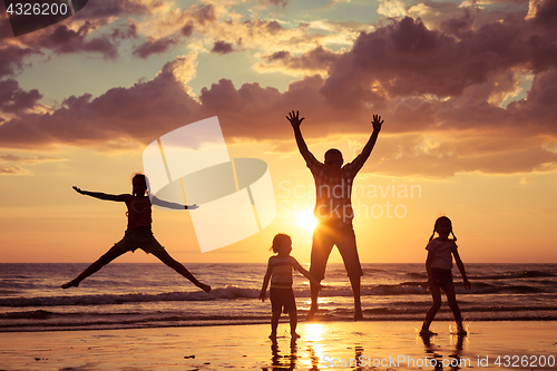 Image of Father and children playing on the beach at the sunset time.