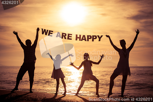 Image of Happy family standing on the beach at the sunset time.