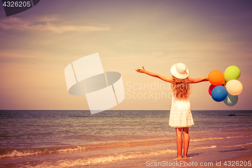 Image of Teen girl with balloons standing on the beach 