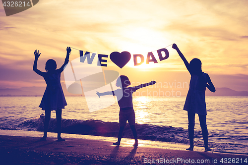 Image of Happy children playing on the beach at the sunset time.