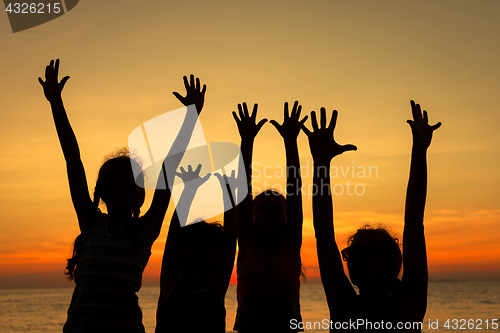 Image of Mother and children playing on the beach at the sunset time.