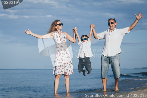 Image of Happy family walking on the beach at the day time.