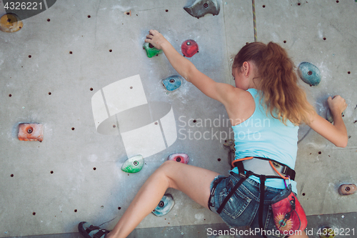 Image of One teenager climbing a rock wall indoor.