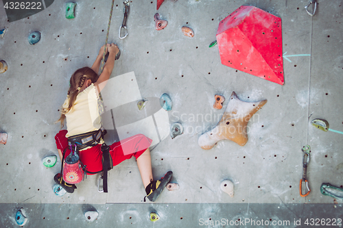 Image of little girl climbing a rock wall indoor