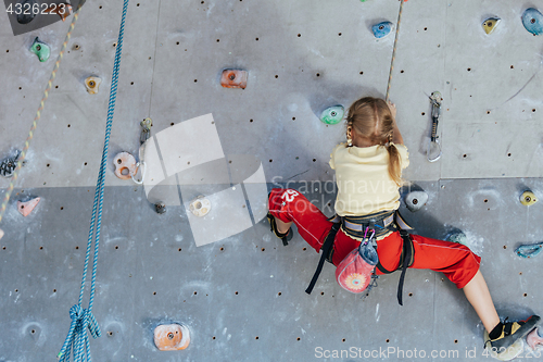 Image of little girl climbing a rock wall indoor