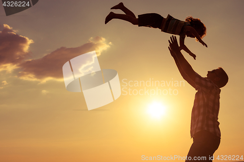 Image of Father and son playing on the beach at the sunset time.