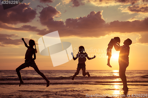 Image of Father and children playing on the beach at the sunset time.