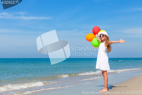Image of Teen girl with balloons standing on the beach