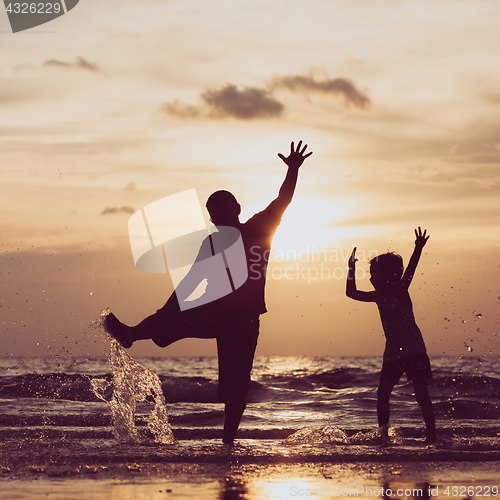 Image of Father and son playing in the park at the sunset time.