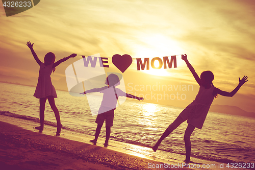 Image of Happy children playing on the beach at the sunset time.