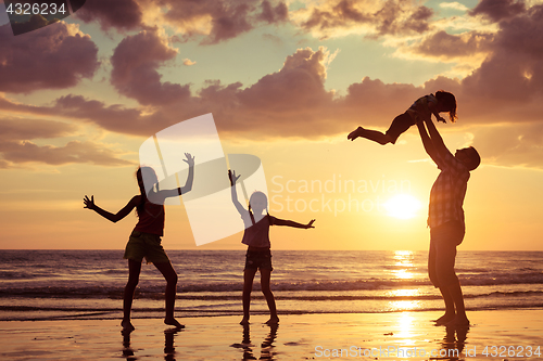 Image of Father and children playing on the beach at the sunset time.