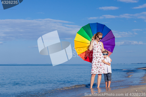 Image of Mother and son playing with umbrella on the beach at the day tim