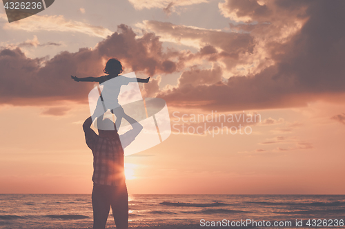 Image of Father and son playing on the beach at the sunset time.