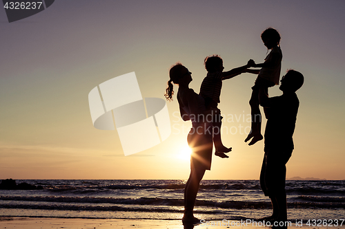 Image of Silhouette of happy family who playing on the beach at the sunse