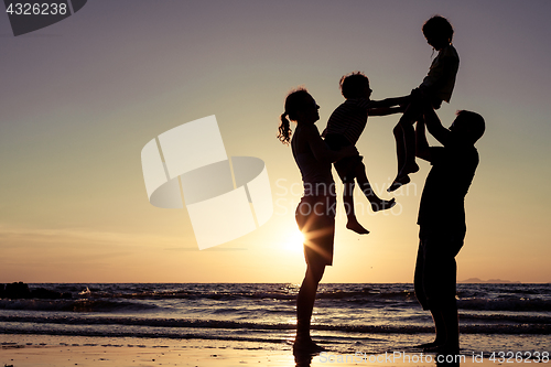 Image of Silhouette of happy family who playing on the beach at the sunse