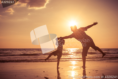 Image of Father and son playing on the beach at the sunset time.